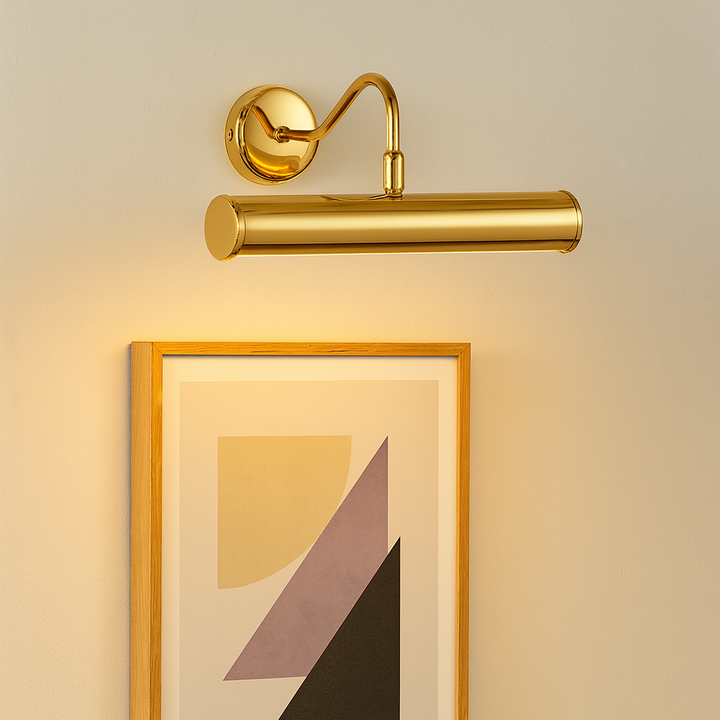 Polished gold picture wall light illuminating framed abstract geometric artwork on a neutral wall