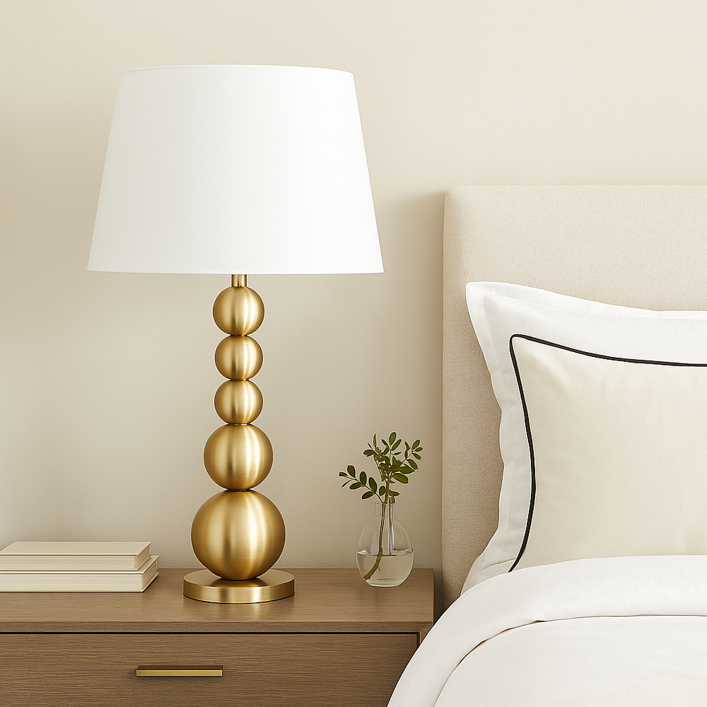 Luxury gold sphere table lamp with white shade styled on a bedside table in a light modern bedroom with neutral décor