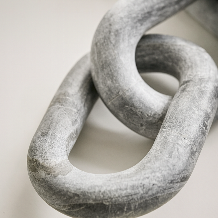 Close-up detail of grey marble chain sculpture showing natural stone texture and veining