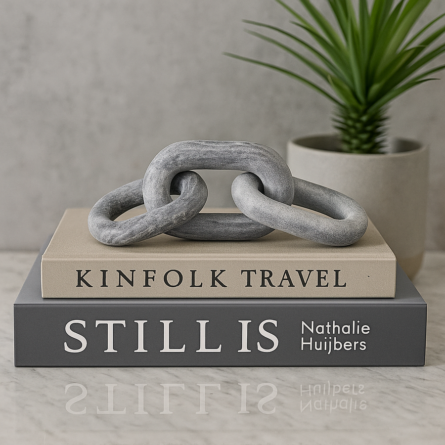 Grey marble chain link sculpture styled on large neutral coffee table books in a modern luxury home interior