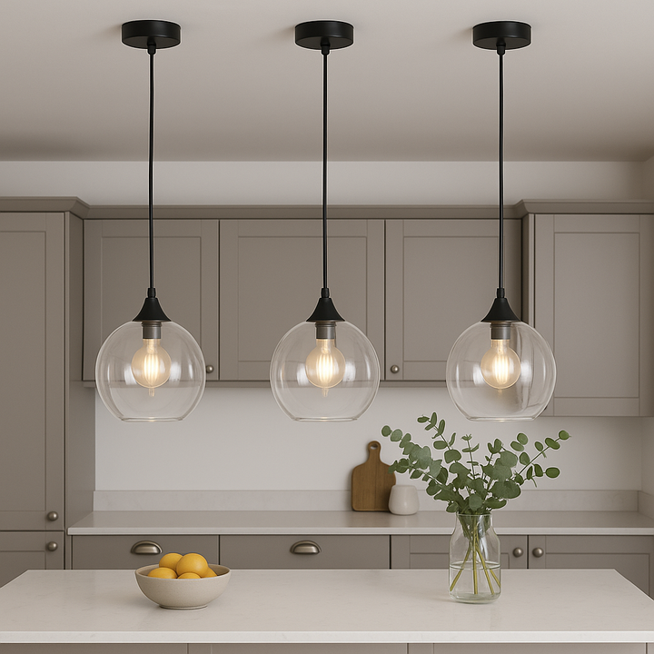 Modern kitchen with three Irvine clear glass pendant lights hung above a white marble island, styled with a bowl of lemons and a glass vase of eucalyptus for subtle luxury décor.