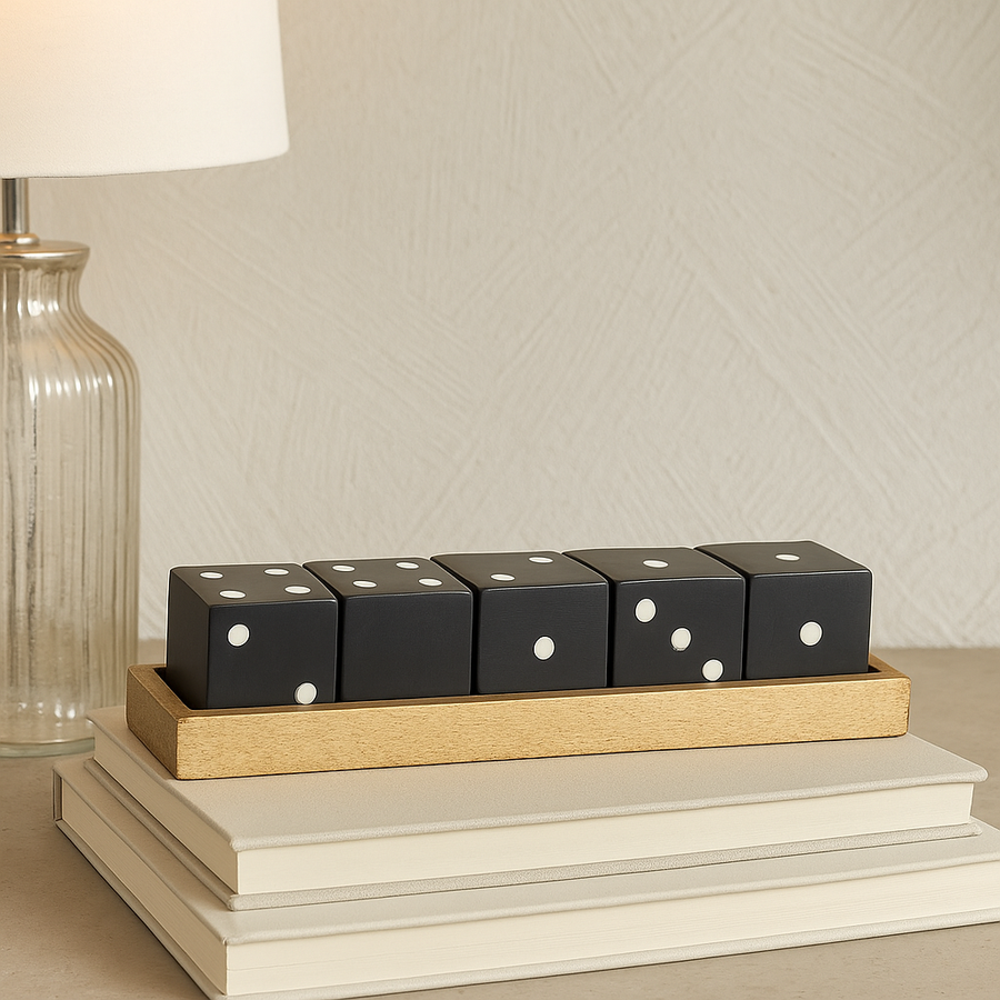 Luxury black wooden dice set in gold tray displayed on books in modern home décor setting