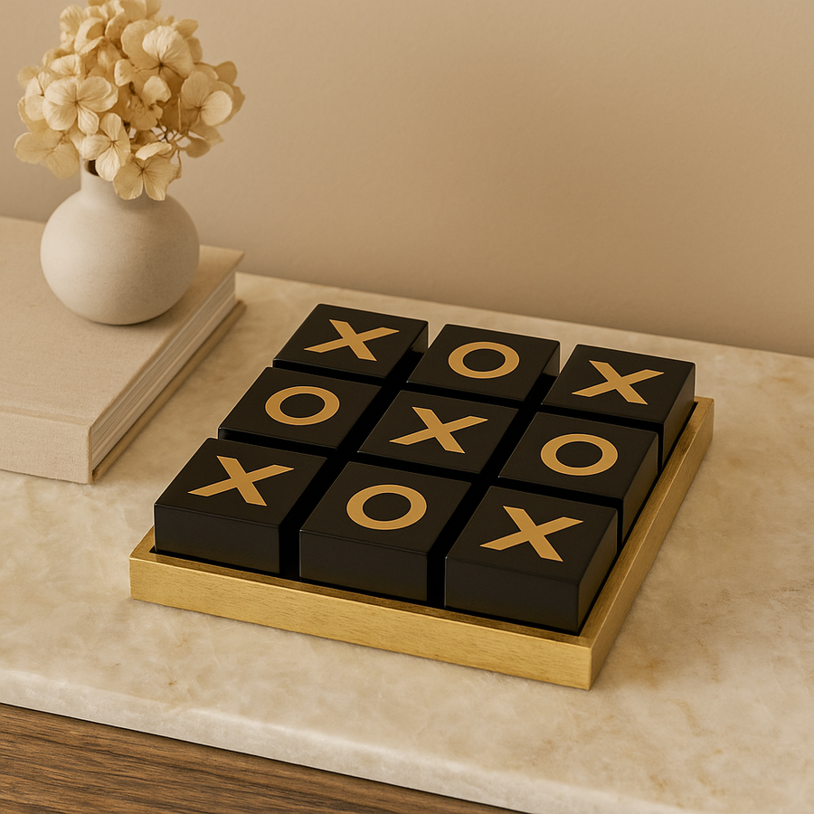 Luxury black and gold noughts and crosses set on marble table with vase and book