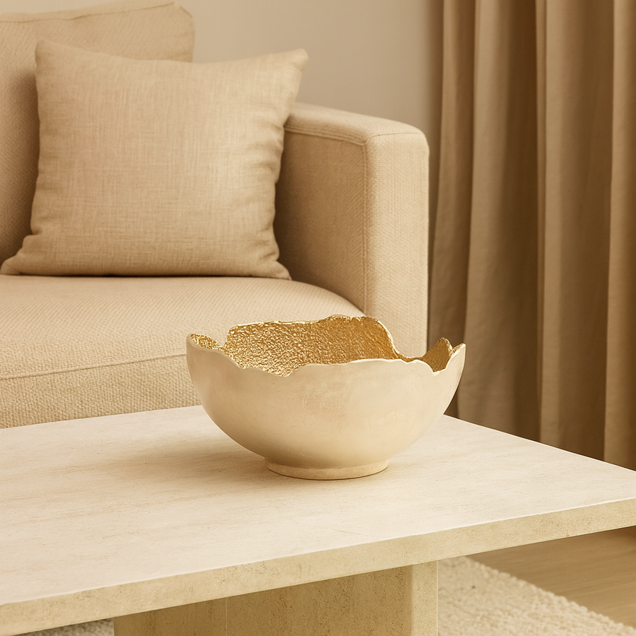 Luxury decorative gold interior bowl styled on a modern coffee table in a neutral living room setting.