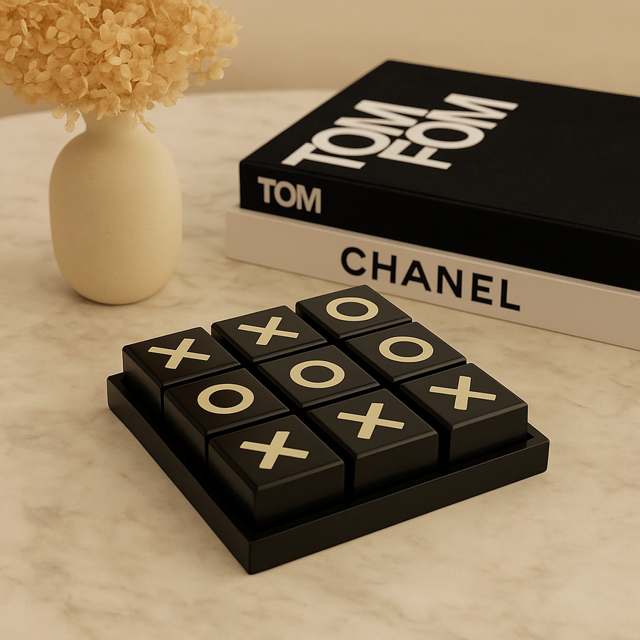 Luxury black and cream noughts and crosses set on marble table with dried flowers and books
