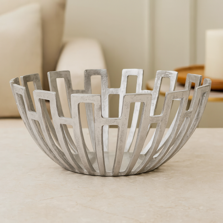 Luxury silver decorative metal bowl with open lattice design styled on marble surface in a modern neutral living space