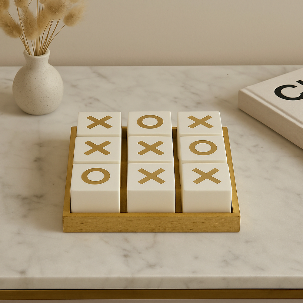 Luxury white and gold noughts and crosses set on marble table with vase and book
