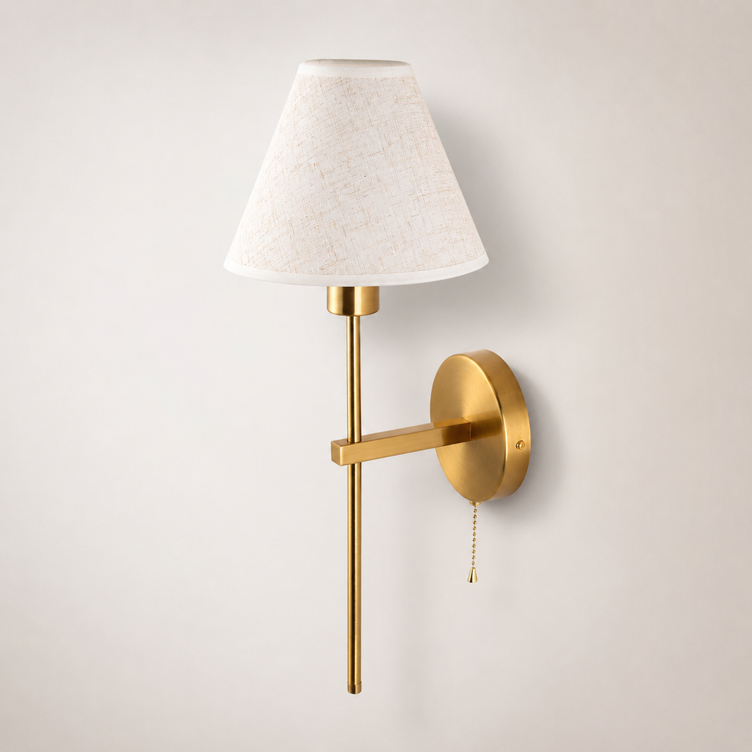 Mahon brass wall light with cream fabric shade and pull cord switch.