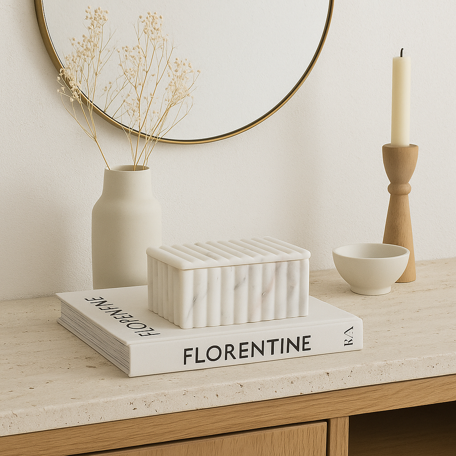 White marble fluted storage box styled on a Nordic media wall unit with books, vase, and candle accessories.