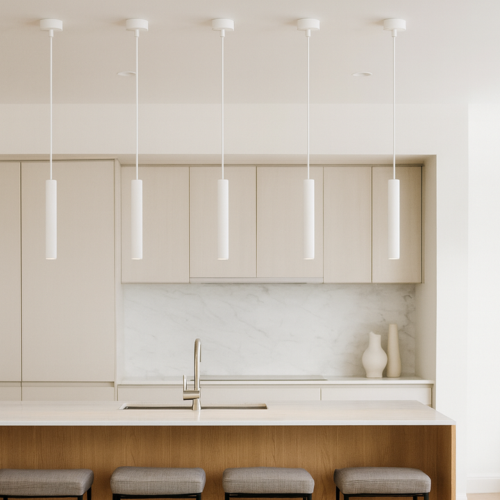 Milan white pendant lights in a modern kitchen, five slim cylindrical pendants hung above a marble island with light cabinetry and bar stools.