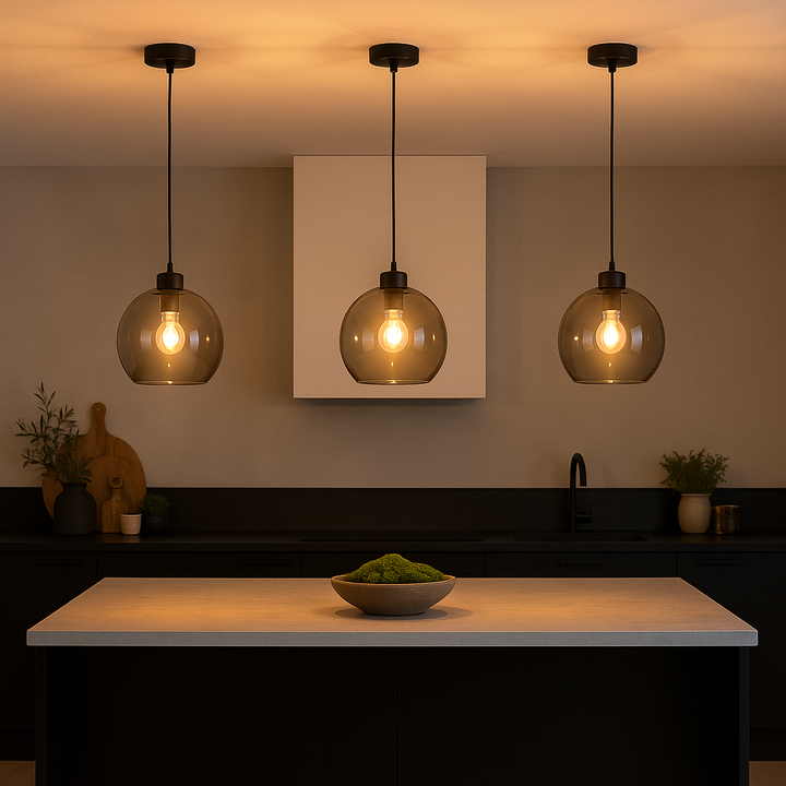 Modern kitchen with three smoked glass pendant lights gently lit above a marble island with green moss bow