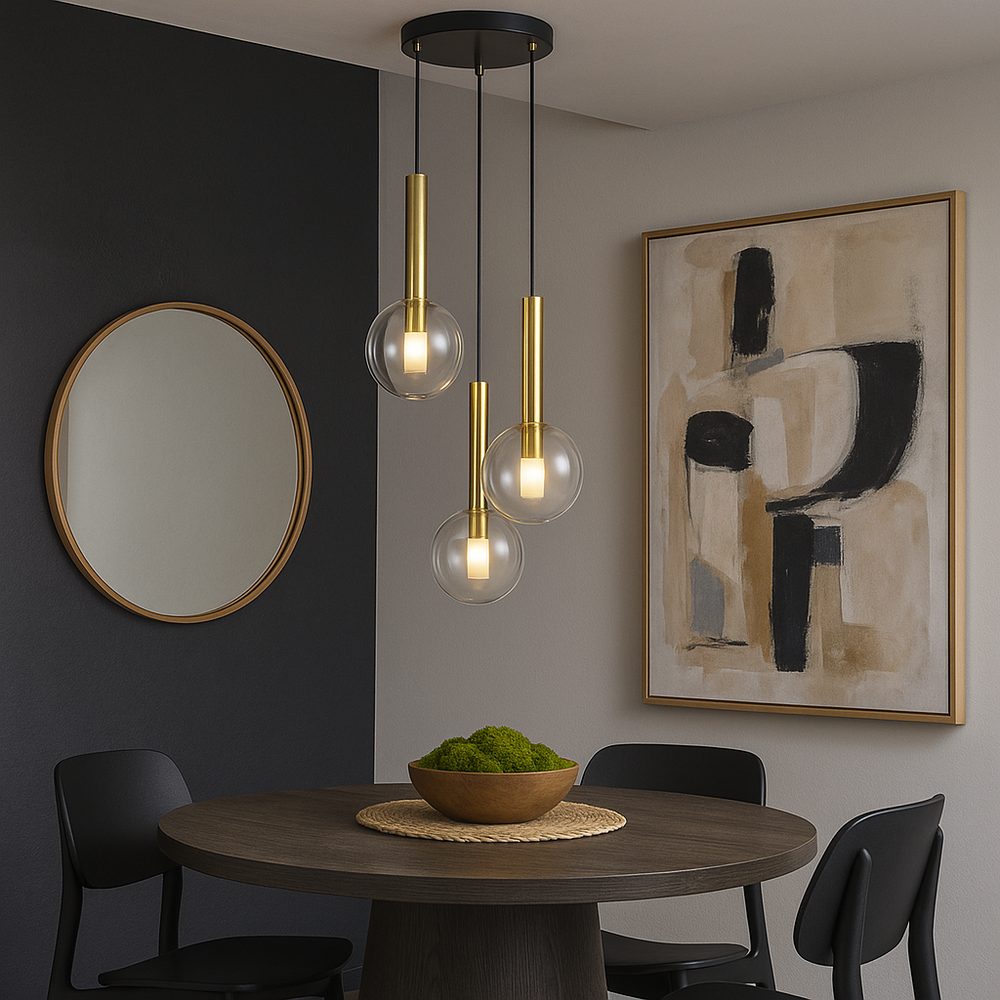 Luxury brass and glass pendant light hanging above a round dining table with green moss bowl, black chairs, wall mirror and abstract artwork in a modern dining room.