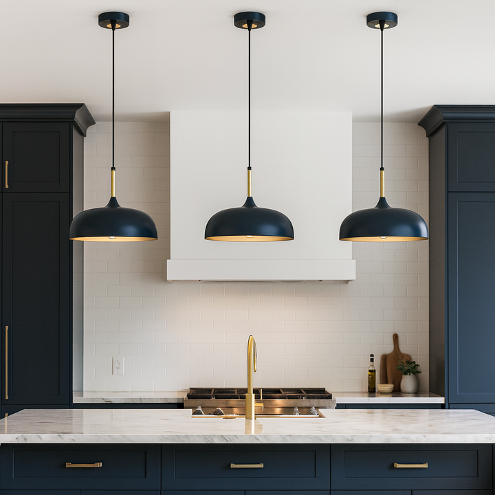 Modern kitchen with three navy and gold pendant lights above a large marble island, navy cabinets with gold handles, and white tile backsplash.