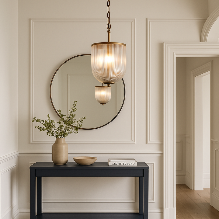 Ribbed glass pendant light with bronze trim hanging in a modern Georgian hallway, styled with a navy console table, round mirror, and decorative accents.