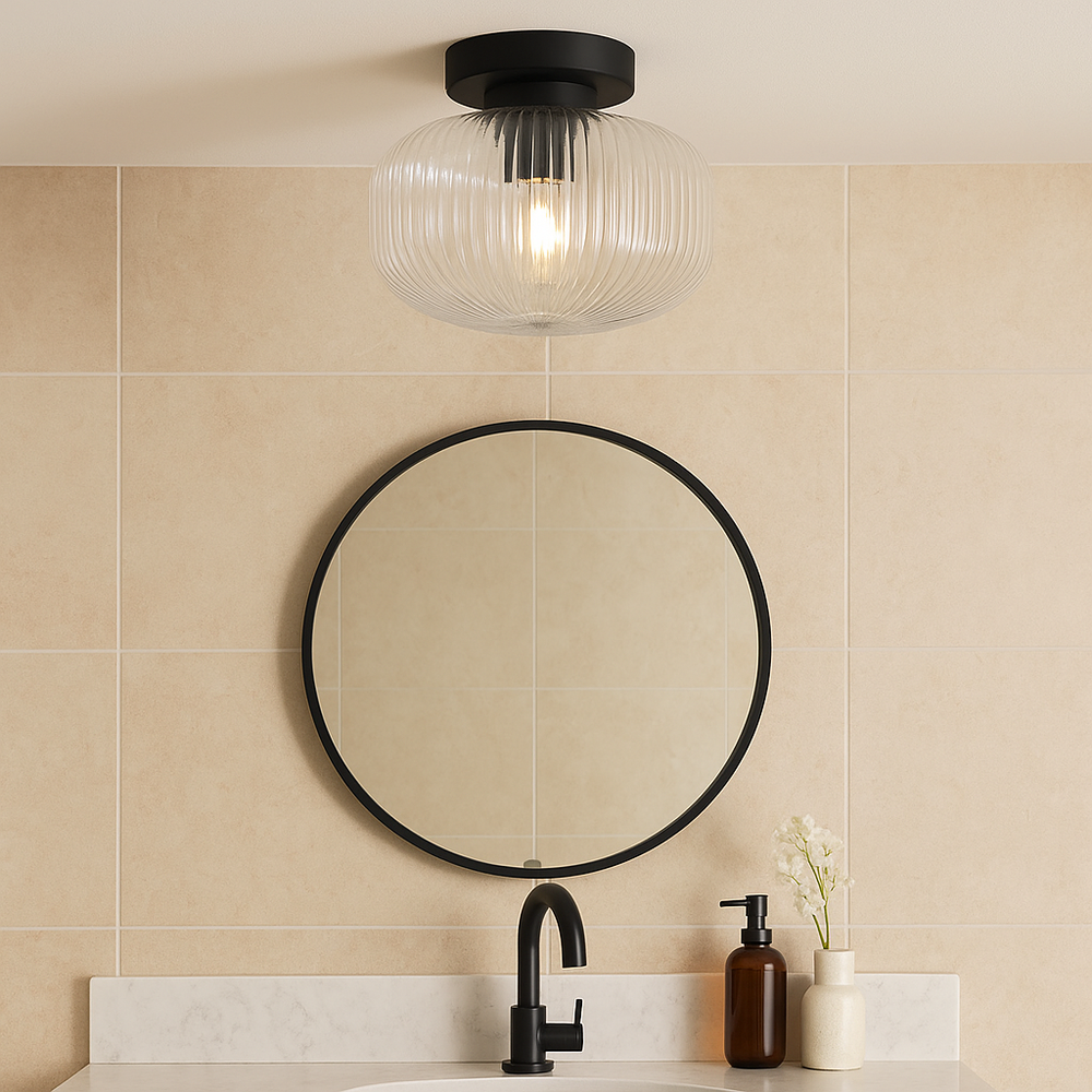 Arlo black flush ceiling light with clear ribbed glass shade in a luxury bathroom, styled with black framed mirror and marble vanity.