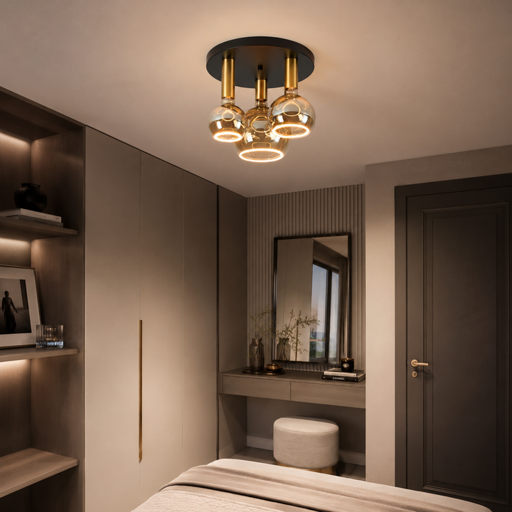 Roma small 3 light flush ceiling light with black ceiling plate, gold holders and smoked Roma Aura bulbs in a luxury bedroom setting.