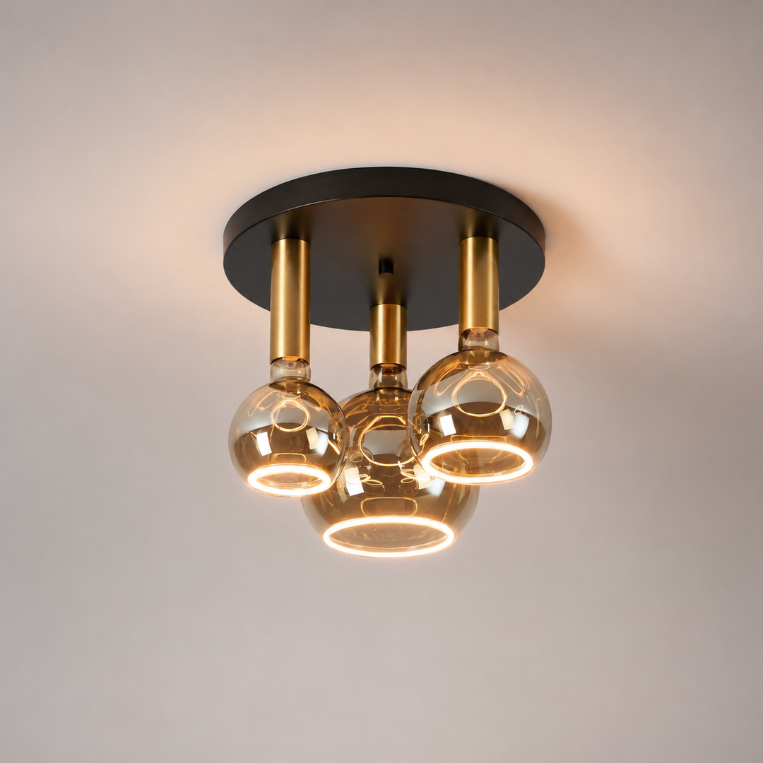 Roma small 3 light flush ceiling light with black ceiling plate, gold holders and smoked Roma Aura bulbs in a luxury square hero image.