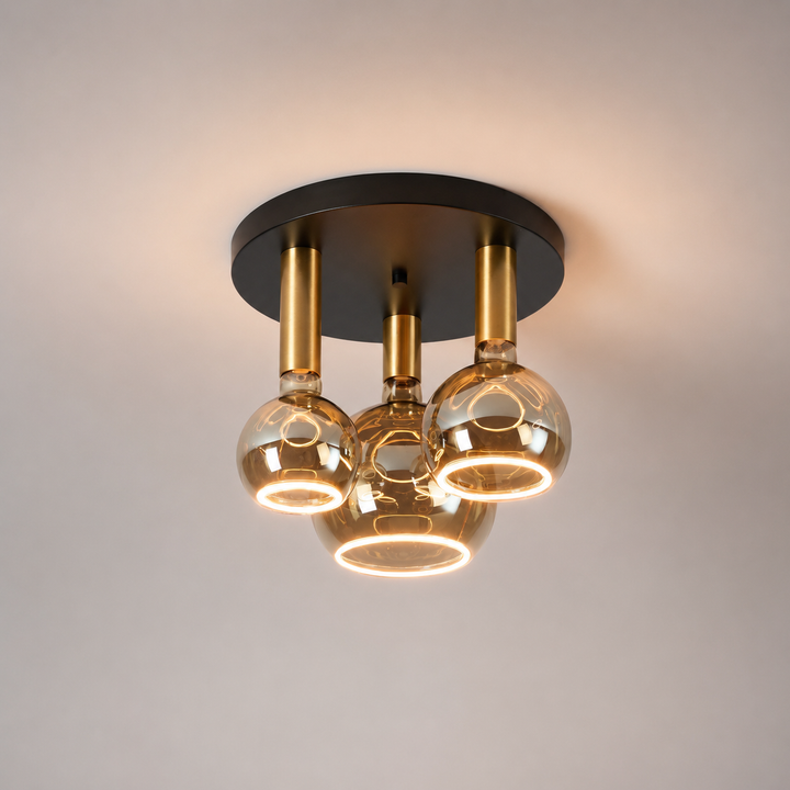 Roma small 3 light flush ceiling light with black ceiling plate, gold holders and smoked Roma Aura bulbs in a luxury square hero image.