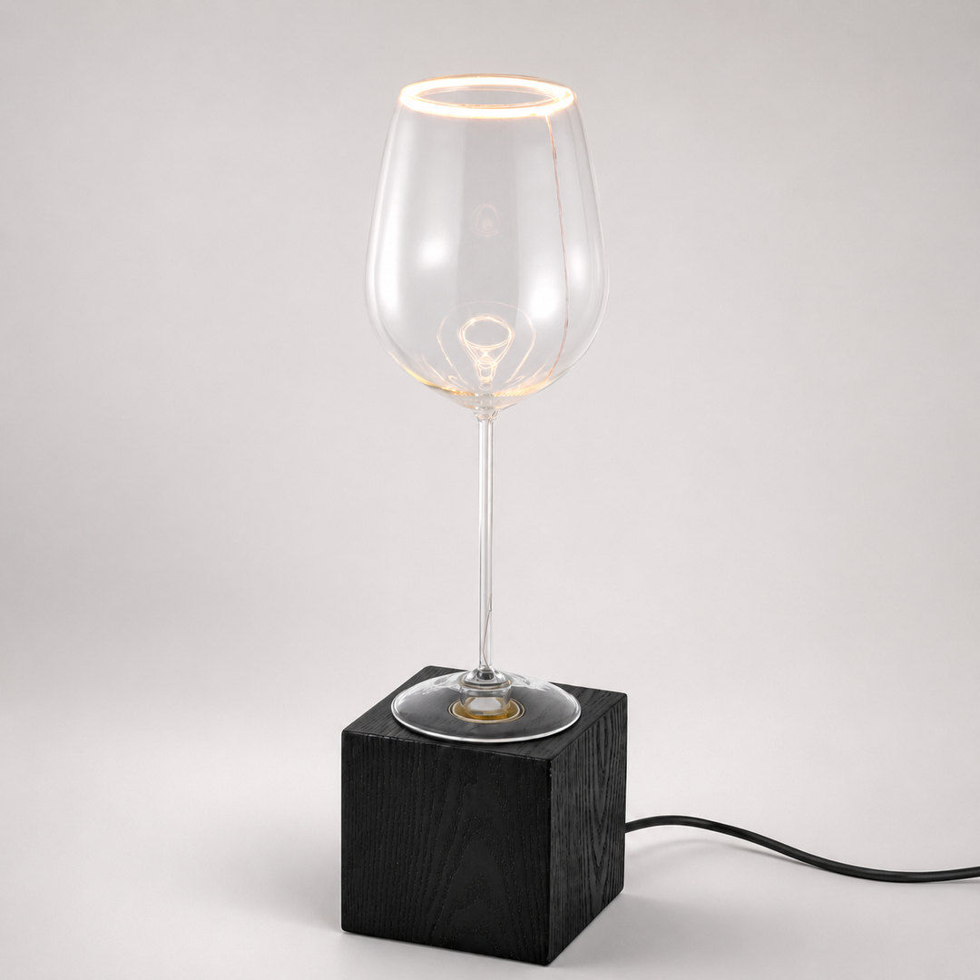 Roma wine glass aura ring table lamp with black wooden base and visible black power cable, illuminated with warm 2200K glow.