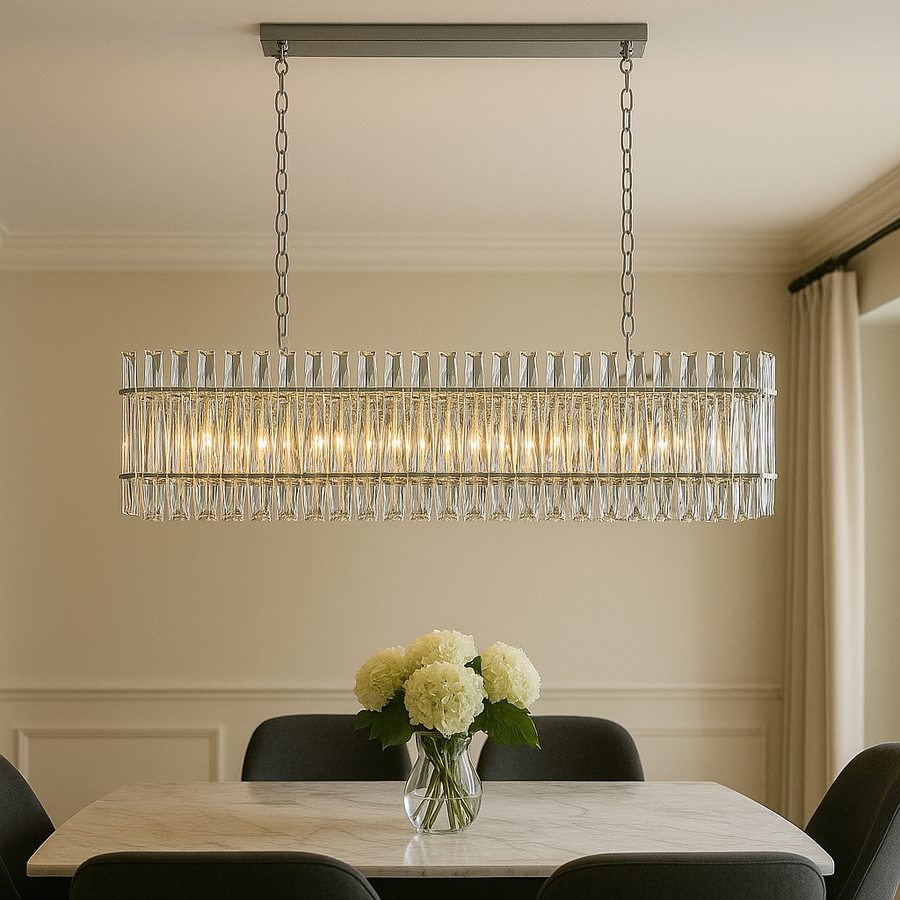 Luxury dining room with a rectangular crystal chandelier featuring a silver frame, hanging over a marble table with white hydrangeas and dark upholstered chairs.