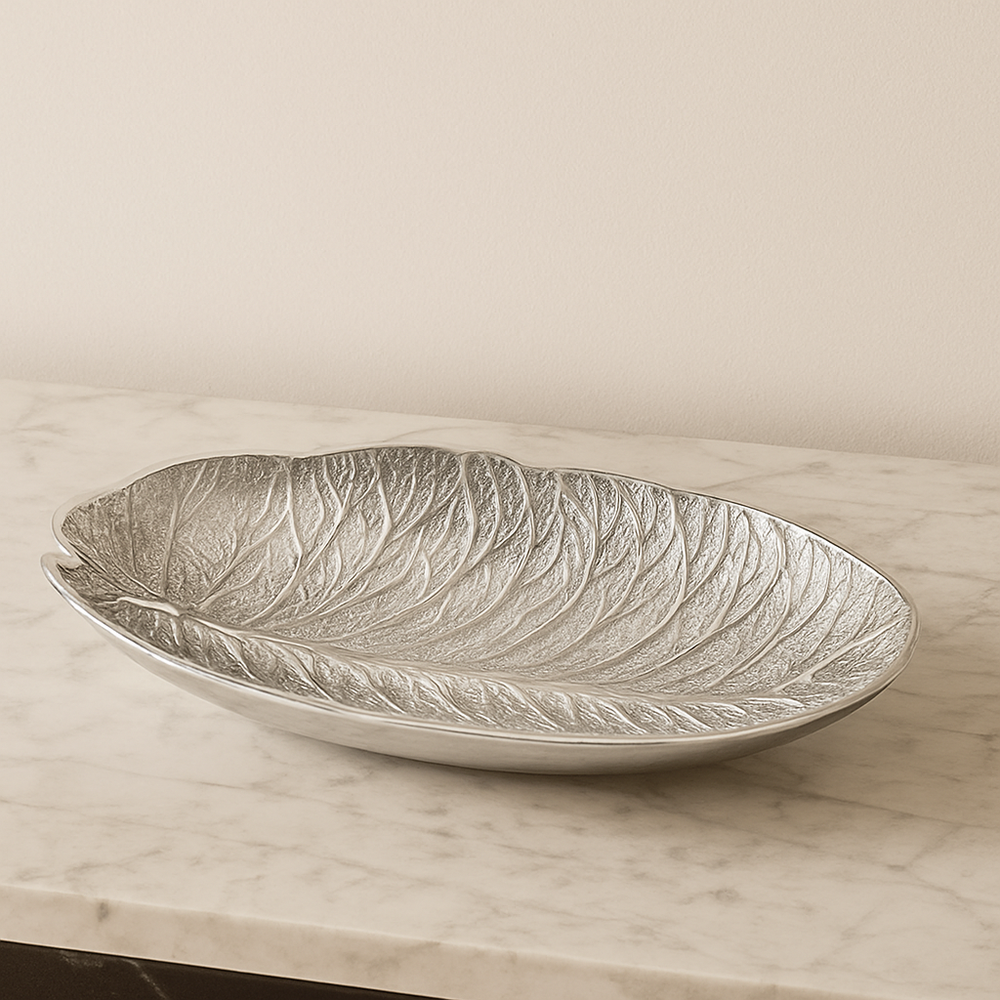 Elegant silver leaf-shaped decorative bowl displayed on a marble surface with a neutral backdrop in a modern luxury home interior