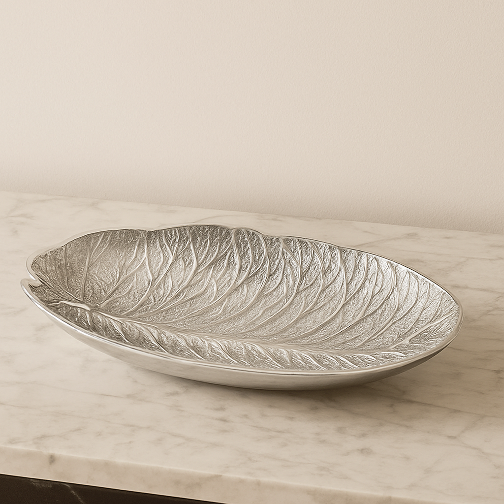 Elegant silver leaf-shaped decorative bowl displayed on a marble surface with a neutral backdrop in a modern luxury home interior