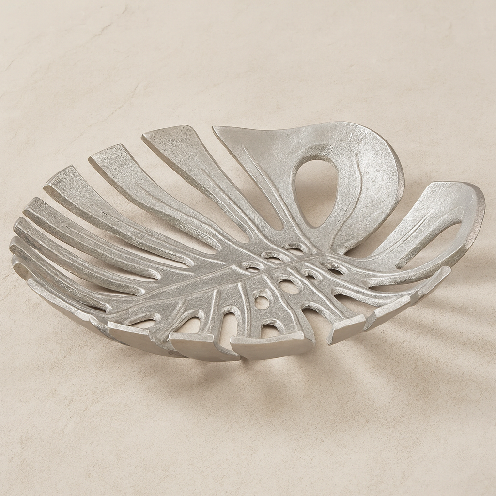 Luxury silver monstera leaf decorative dish with openwork design styled on light neutral marble surface