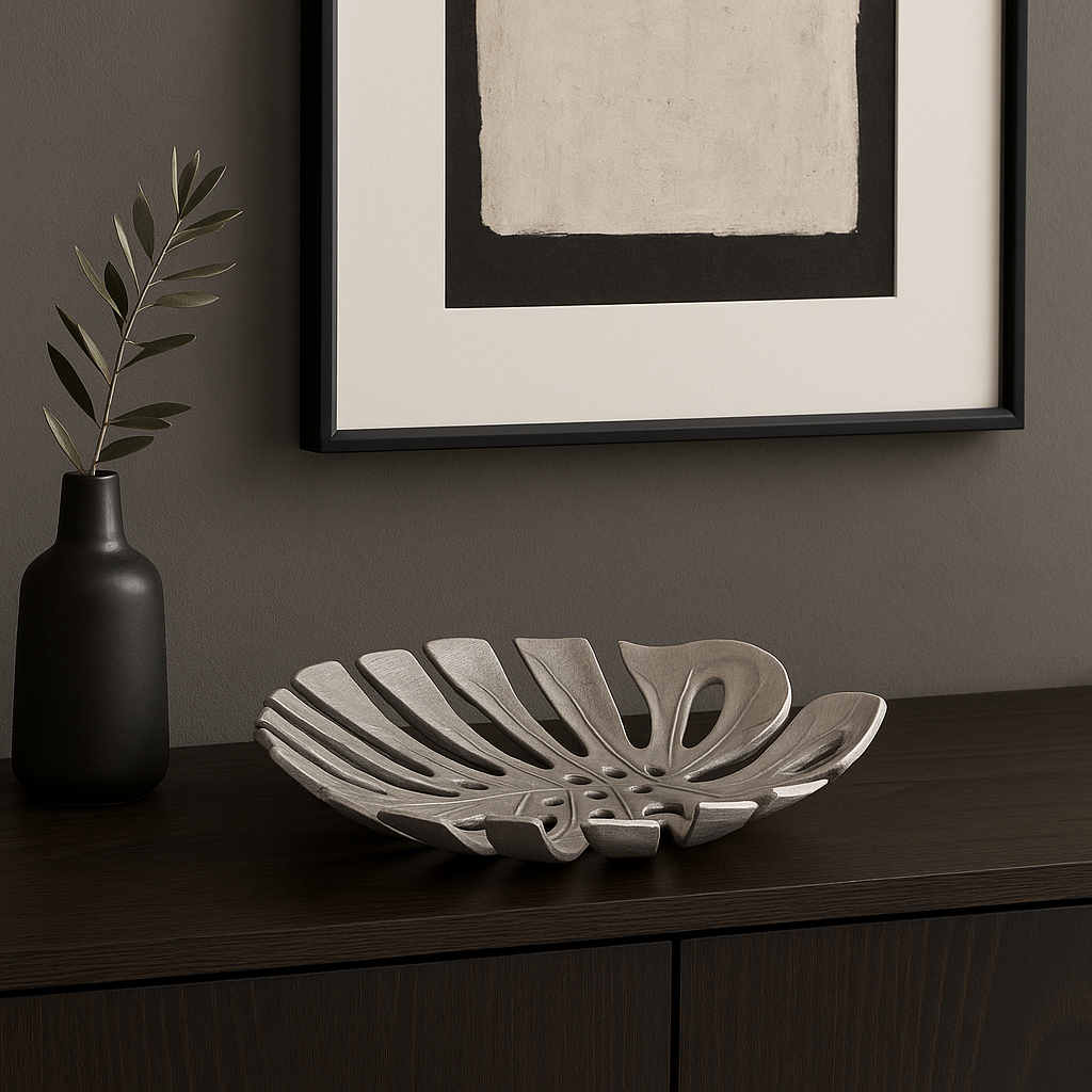 Luxury silver monstera leaf decorative dish styled on a dark wood sideboard with modern artwork and vase in a contemporary home setting