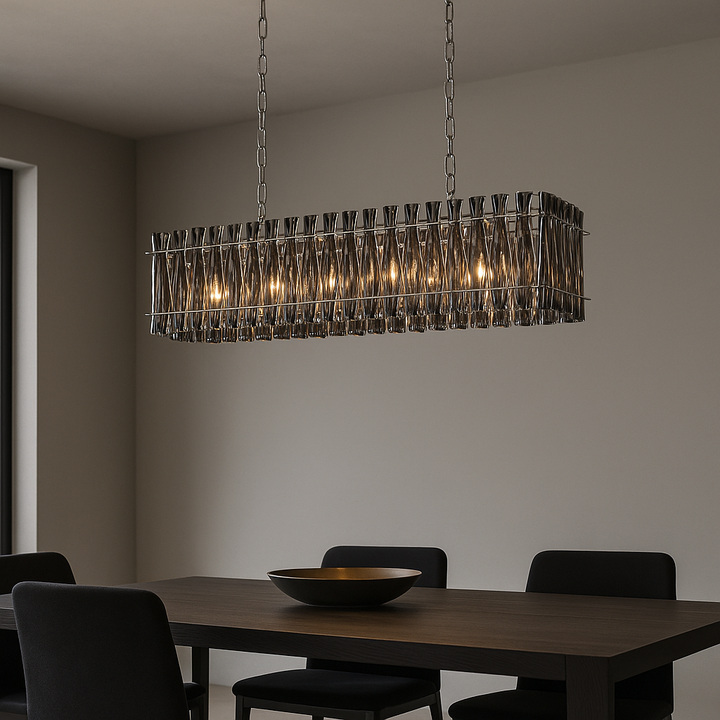 Modern dining room with a smoked crystal rectangular chandelier in a polished silver frame hanging above a dark wood rectangular table, styled with a decorative bowl centerpiece and black upholstered chairs.