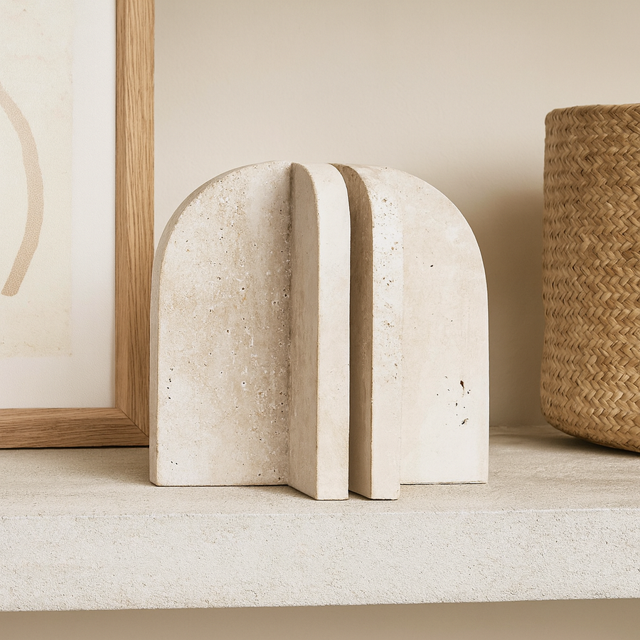 Luxury travertine arch bookends styled on a neutral shelf with artwork and basket decor