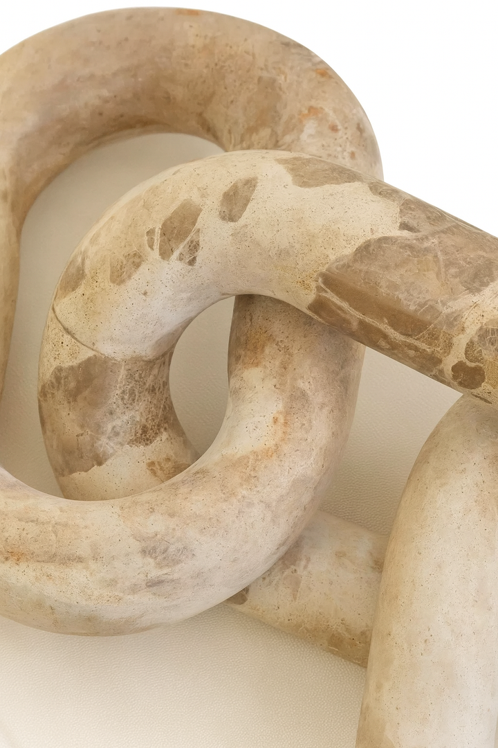 Close-up detail of beige travertine chain sculpture showing natural stone veining and texture