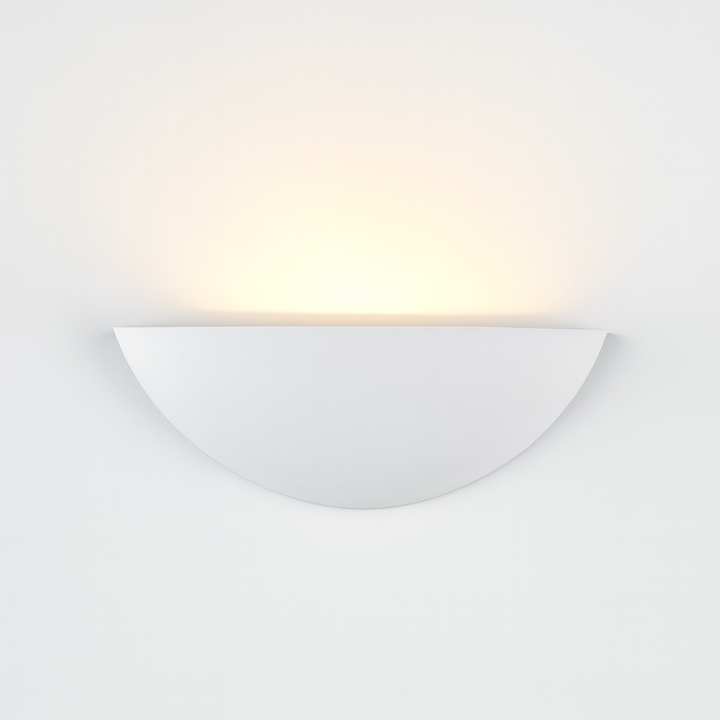White ceramic half-moon wall light with soft upward glow on white background, minimalist paintable design