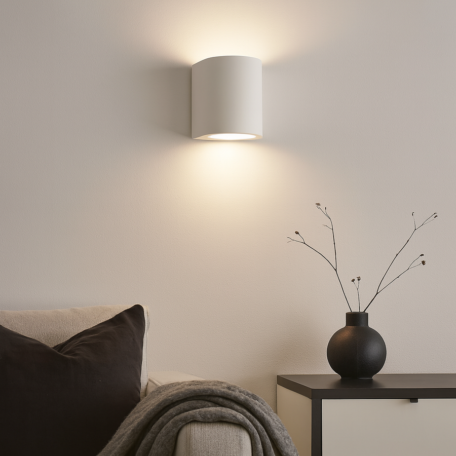 Modern living room with white curved wall light casting soft glow above sofa and sideboard styled with black vase and simple twigs