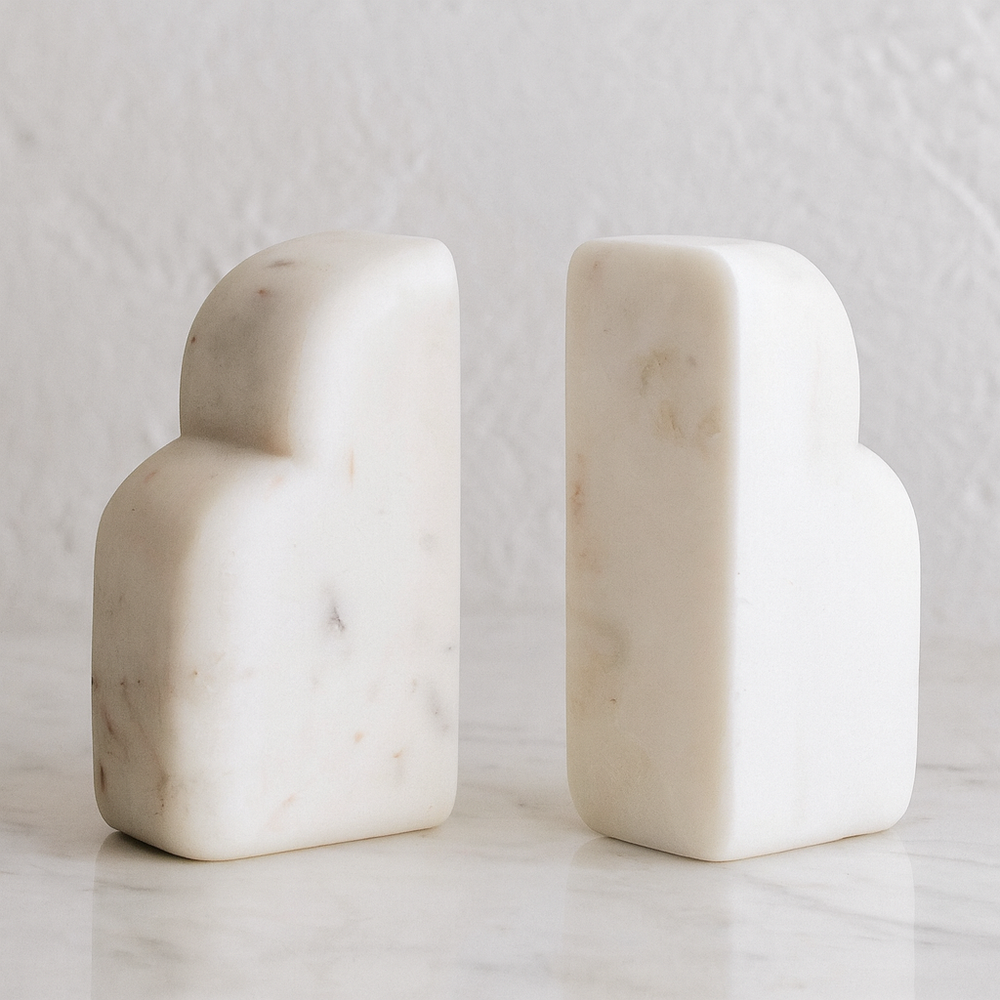 Luxury white marble arched bookends styled on a polished marble surface with a textured neutral wall backdrop