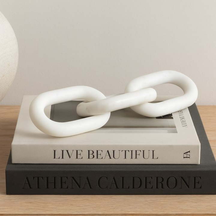 White marble chain link sculpture styled on coffee table books, modern luxury home décor accessory.