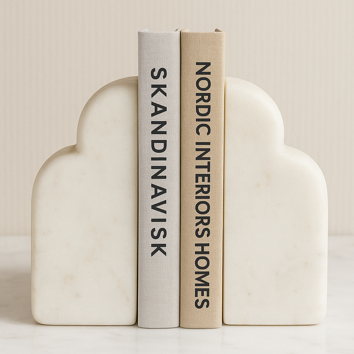 Luxury white marble cloud-shaped bookends with Nordic interior design books on a marble surface
