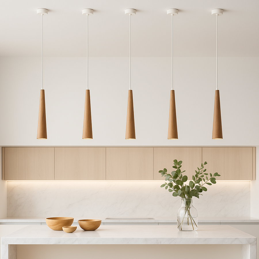Five wooden pendant lights above a white marble island in a Scandinavian modern kitchen with light cabinetry, bowls, and vase greenery.